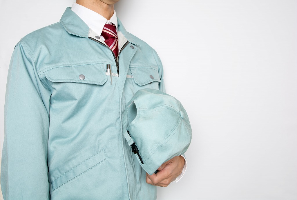 帽子を持つ作業服の男性