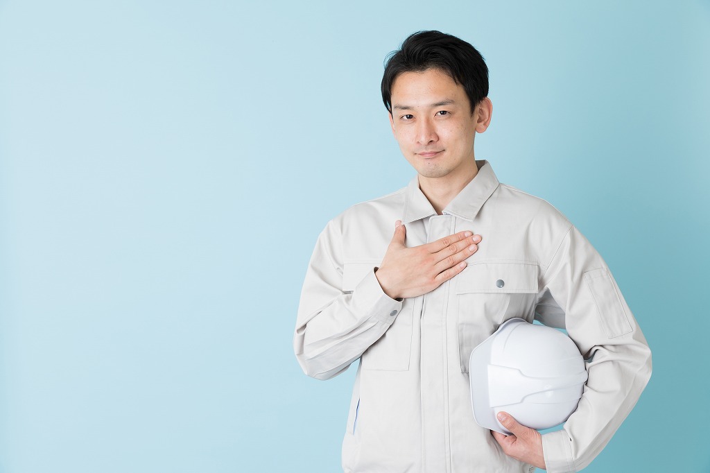 手を胸に当てる作業服の男性