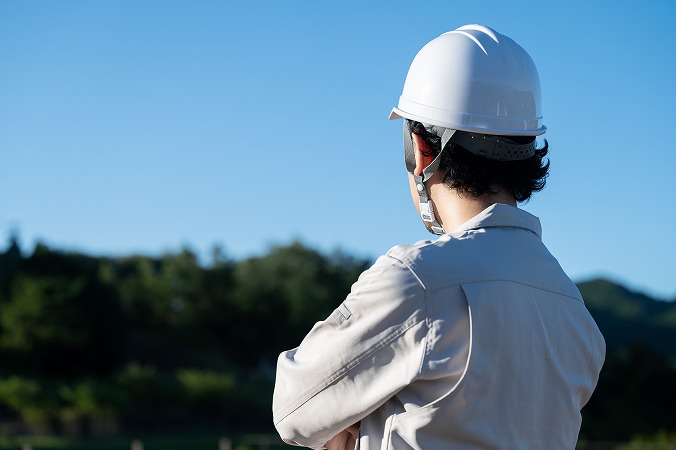 腕を組む作業服の男性
